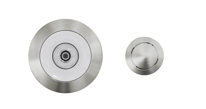 Two Custom Nozzle Color shower drains are displayed on a white background. The drain on the left is larger and circular with a white center, featuring a central hole. The smaller drain on the right is also circular with a brushed metal finish and a central hole.
