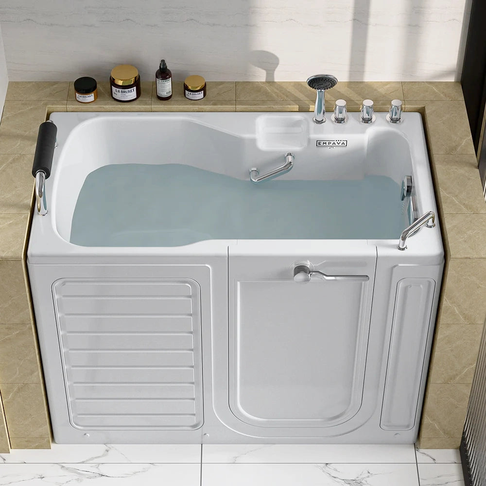 A 54-inch alcove soaking walk-in tub with a right drain, filled with water, is set into a beige-tiled bathroom. The white bathtub features a black headrest, various chrome fixtures, and a side door with a handle. Shampoo and soap containers are placed on the edge of the tub.