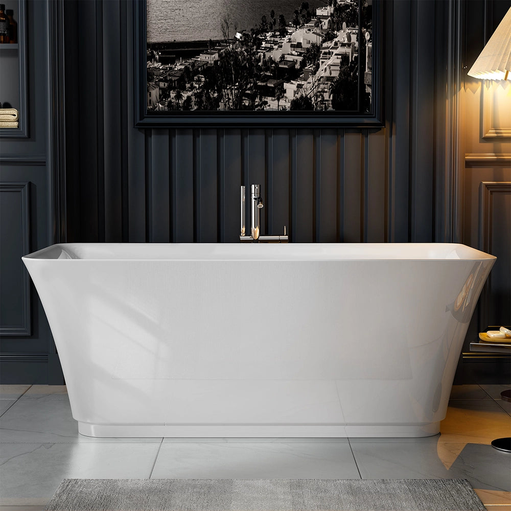 A modern bathroom featuring a freestanding installation of the 59" Freestanding Soaking Tub with Center Drain, showcasing its sleek lines and lightweight acrylic craftsmanship, positioned against a dark paneled wall. Above the tub hangs a large monochromatic photograph. To the right, a warm lamp casts a cozy glow on the scene. Light-colored tiles and a rug complete the look.