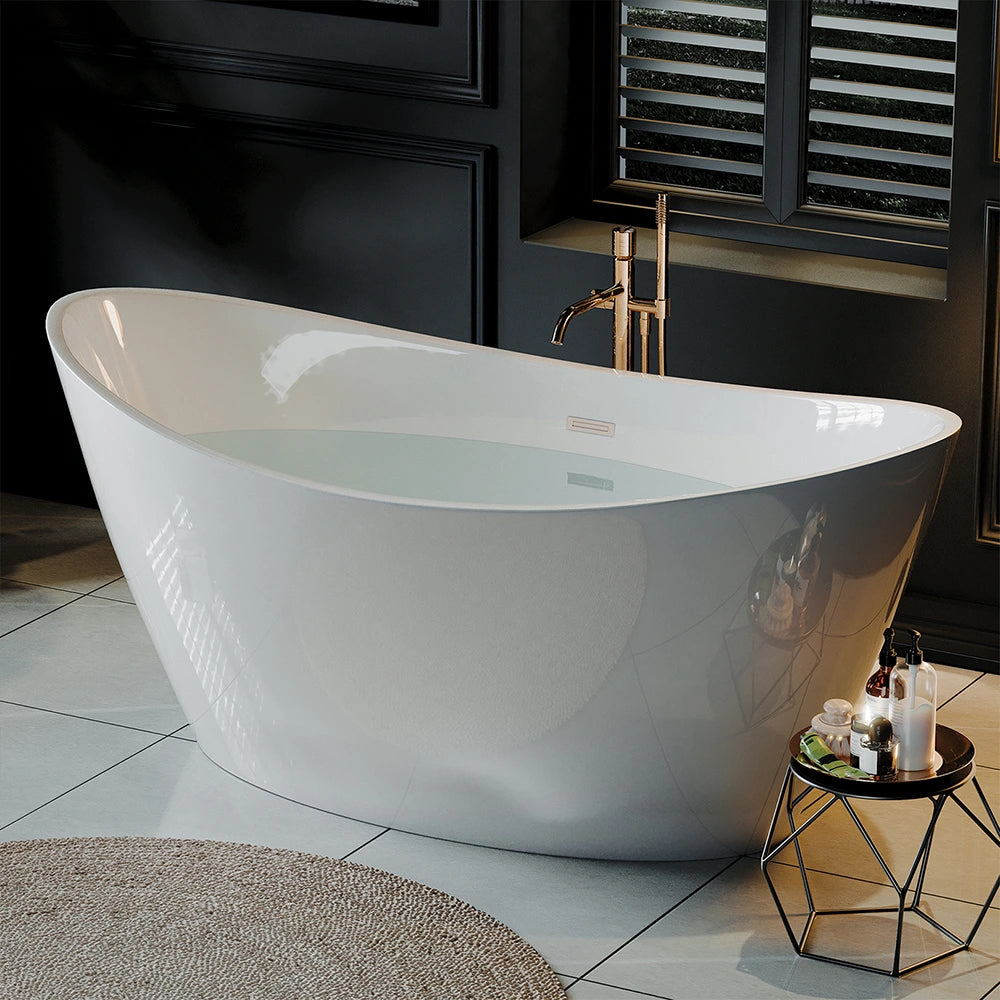 The 67" Freestanding Soaking Tub with Center Drain, made of sleek white acrylic material and filled with water, sits on a tiled floor next to a small round table. The bathtub’s freestanding design holds candles, a towel, and bath products. The background showcases dark walls with decorative paneling and a window adorned with horizontal blinds.