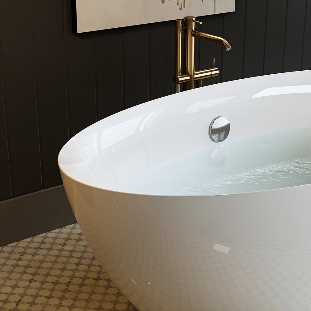 The 71" Freestanding Soaking Tub with Center Drain, boasting a modern, white finish and an ergonomic curved design, is partially filled with water. It is set against a dark paneled wall featuring a brass faucet extending from it. The floor showcases a patterned tile design in muted tones.