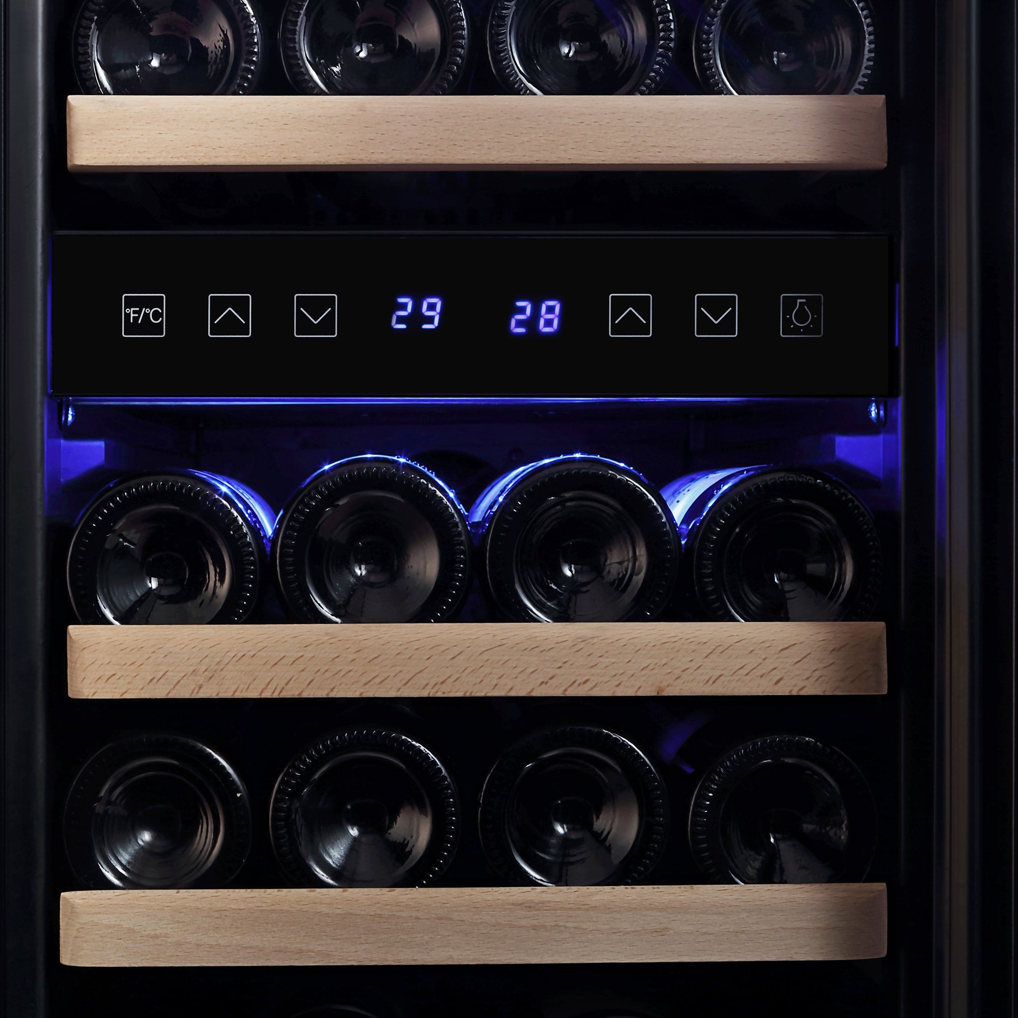 Close-up view of an Empava 15 Inch Dual Zone Small Wine Fridge with wooden shelves holding wine bottles. The digital display shows temperatures in Celsius and Fahrenheit, set to 29 and 28 degrees. Blue lighting elegantly illuminates the interior.