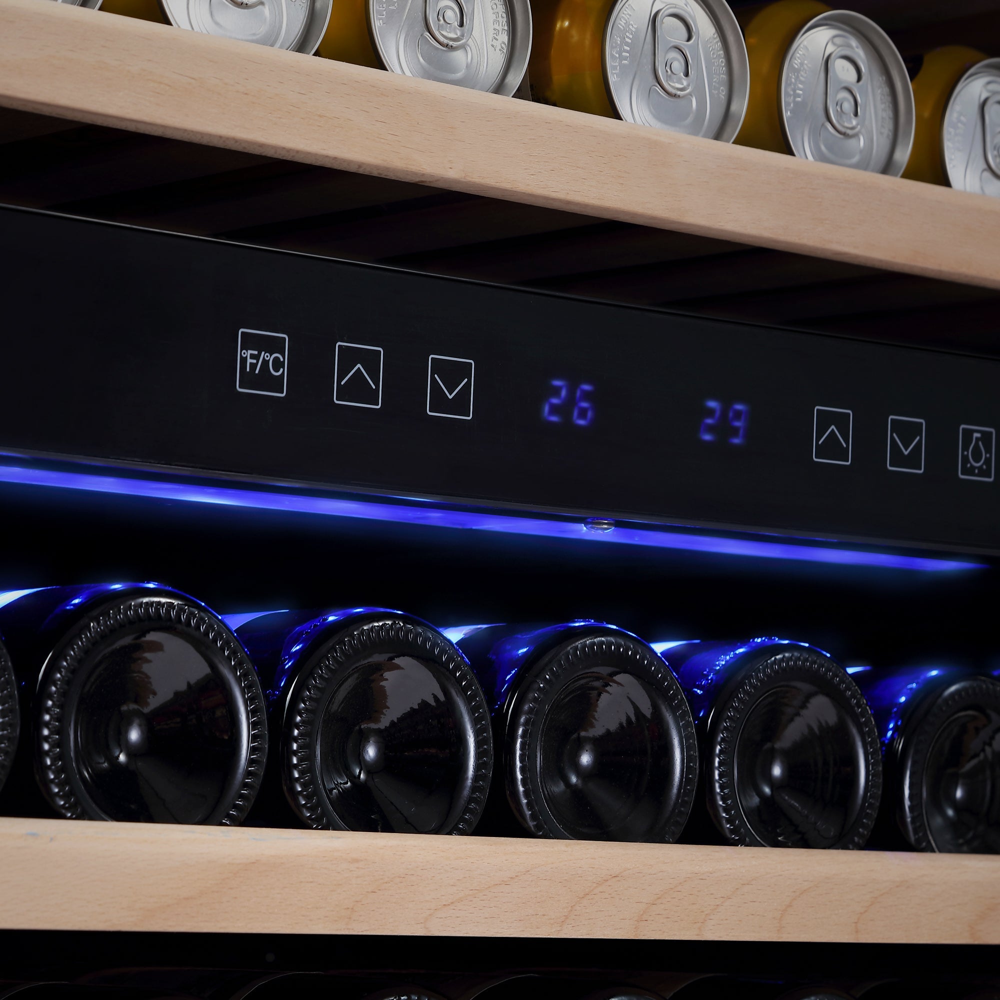 Close-up of the Empava 24 Inch Fridge Dual Zone Wine & Beverage Cooler, highlighting the digital temperature displays set to 26°C and 29°C. The cooler's sleek black control panel features touch buttons, with shelves holding wine bottles and canned drinks visible below and above.