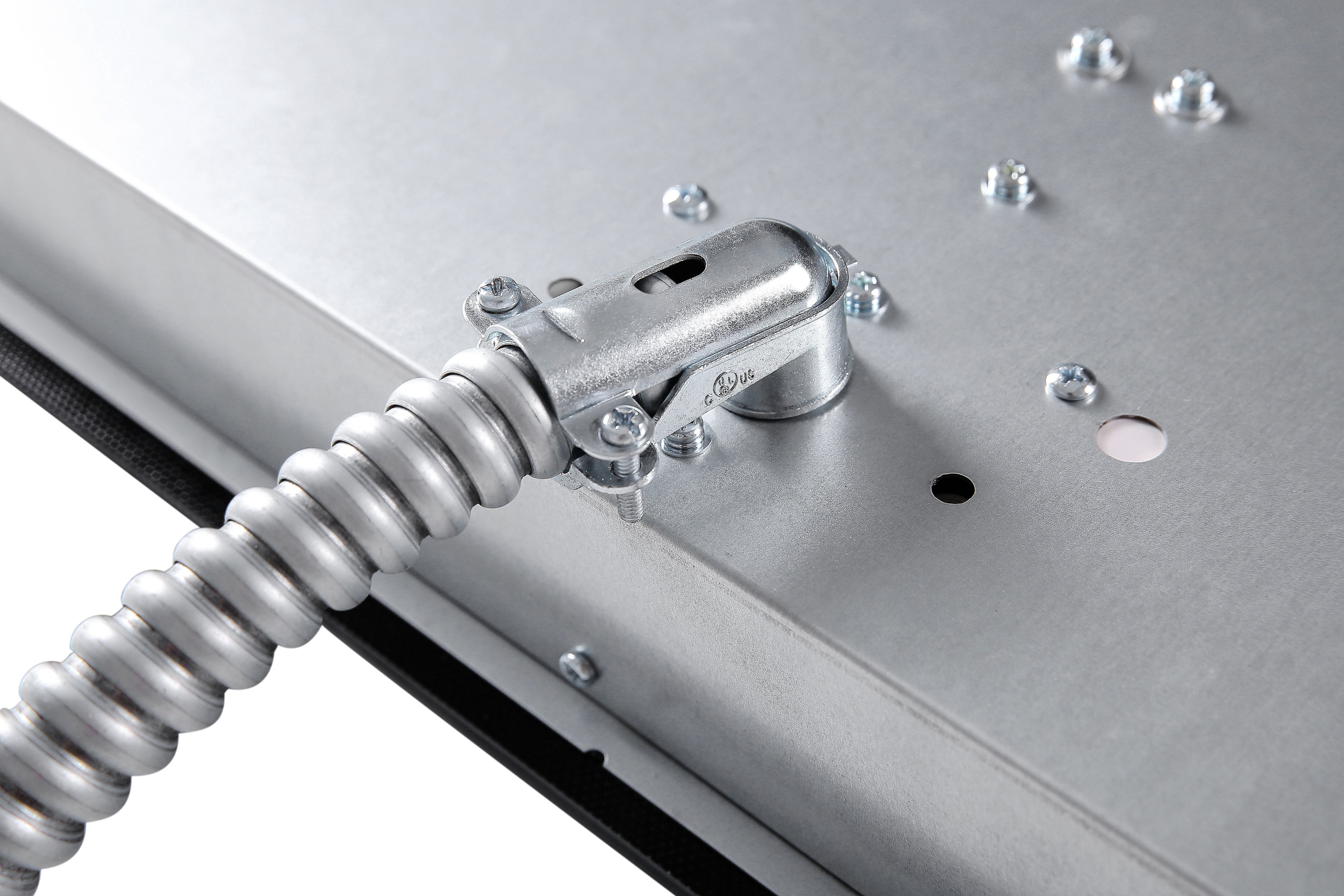 A close-up view of a metallic electrical junction box with a flexible conduit attached, showcasing the high-quality craftsmanship reminiscent of the Empava 30 Inch Induction Cooktop. The conduit has a bent metallic fitting connected to the box, and the surface features multiple screws and several holes.