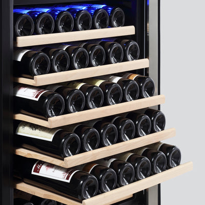 The Empava 55" Tall Dual Zone 100 Bottle Wine Fridge is filled with multiple rows of wine bottles stored horizontally on wooden racks, with their necks facing outward. Featuring dual temperature zones, the dim lighting highlights the various labels and colors of the wines, ensuring optimal conditions to prevent wine oxidization.