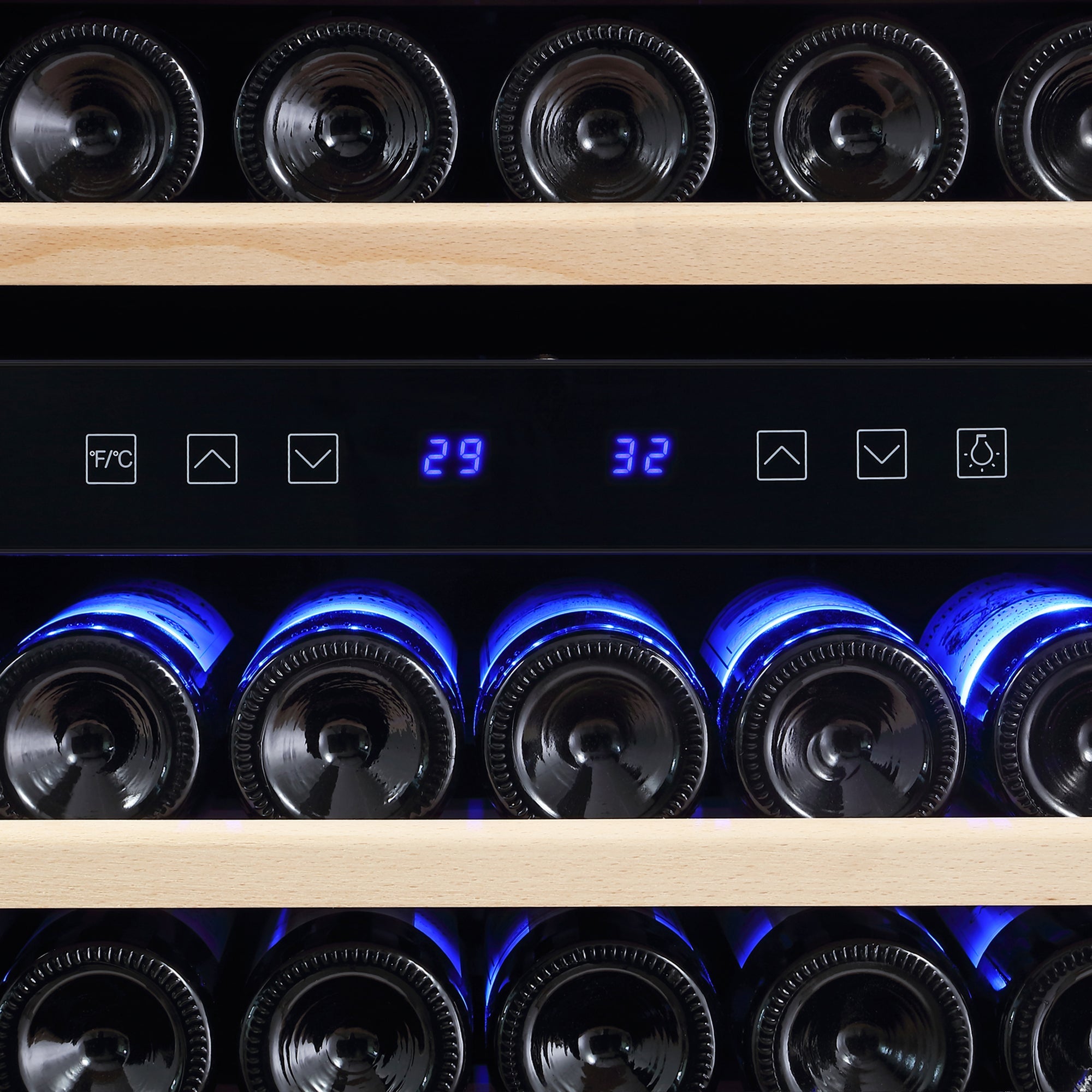 A close-up of the Empava 55" Tall Dual Zone 100 Bottle Wine Fridge shows two shelves filled with wine bottles lying on their sides. The digital display on the fridge reads "29" and "32," indicating dual temperature settings to prevent wine oxidation. Blue LED lights illuminate the bottles from below.