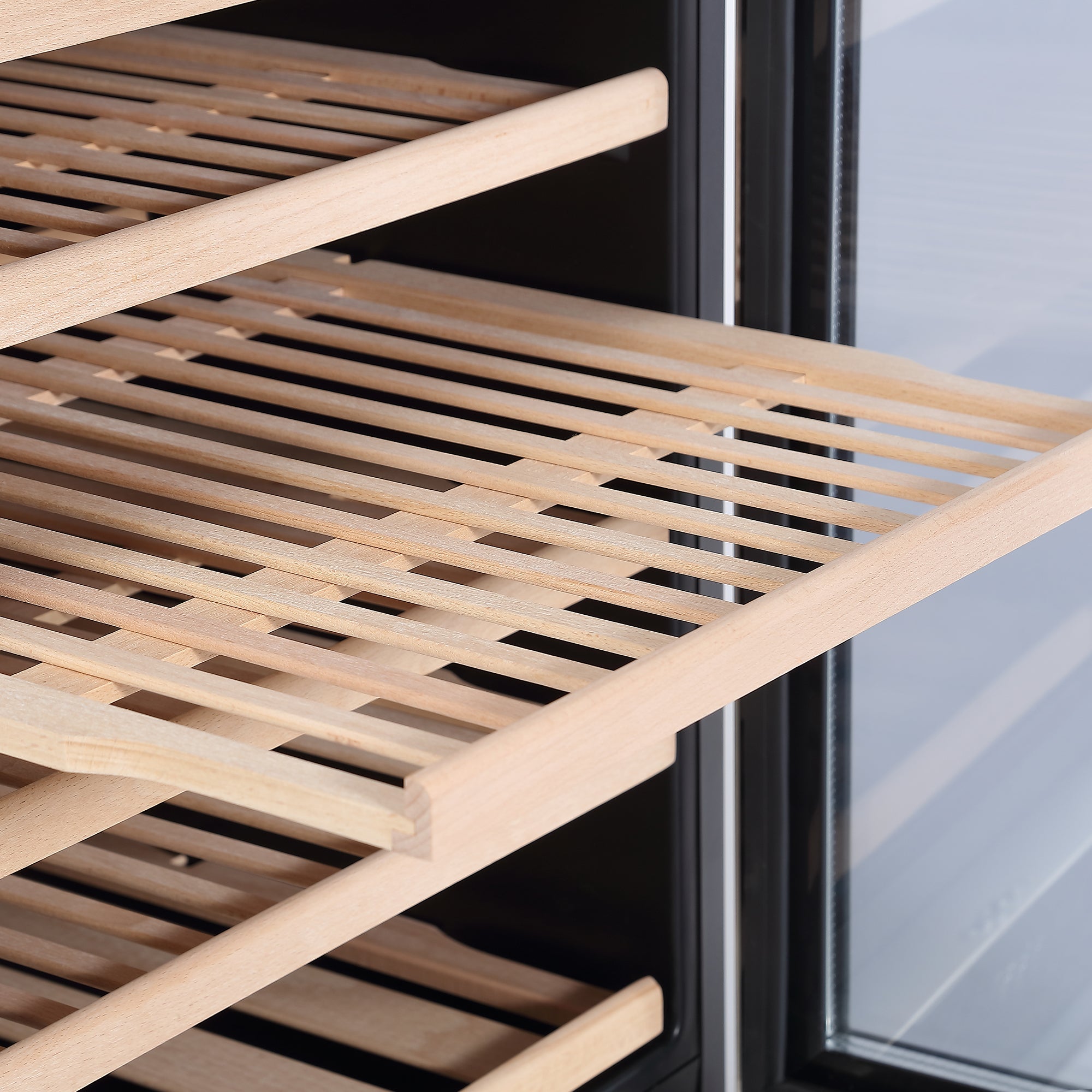 Close-up of a wooden wine rack shelf inside an Empava Wine Cooler 70" Tall Wine Fridge. The slatted, movable shelf is partially pulled out, showcasing the natural wood grain and the grooves where wine bottles would be stored. The fridge's enormous capacity and doorframe are visible.