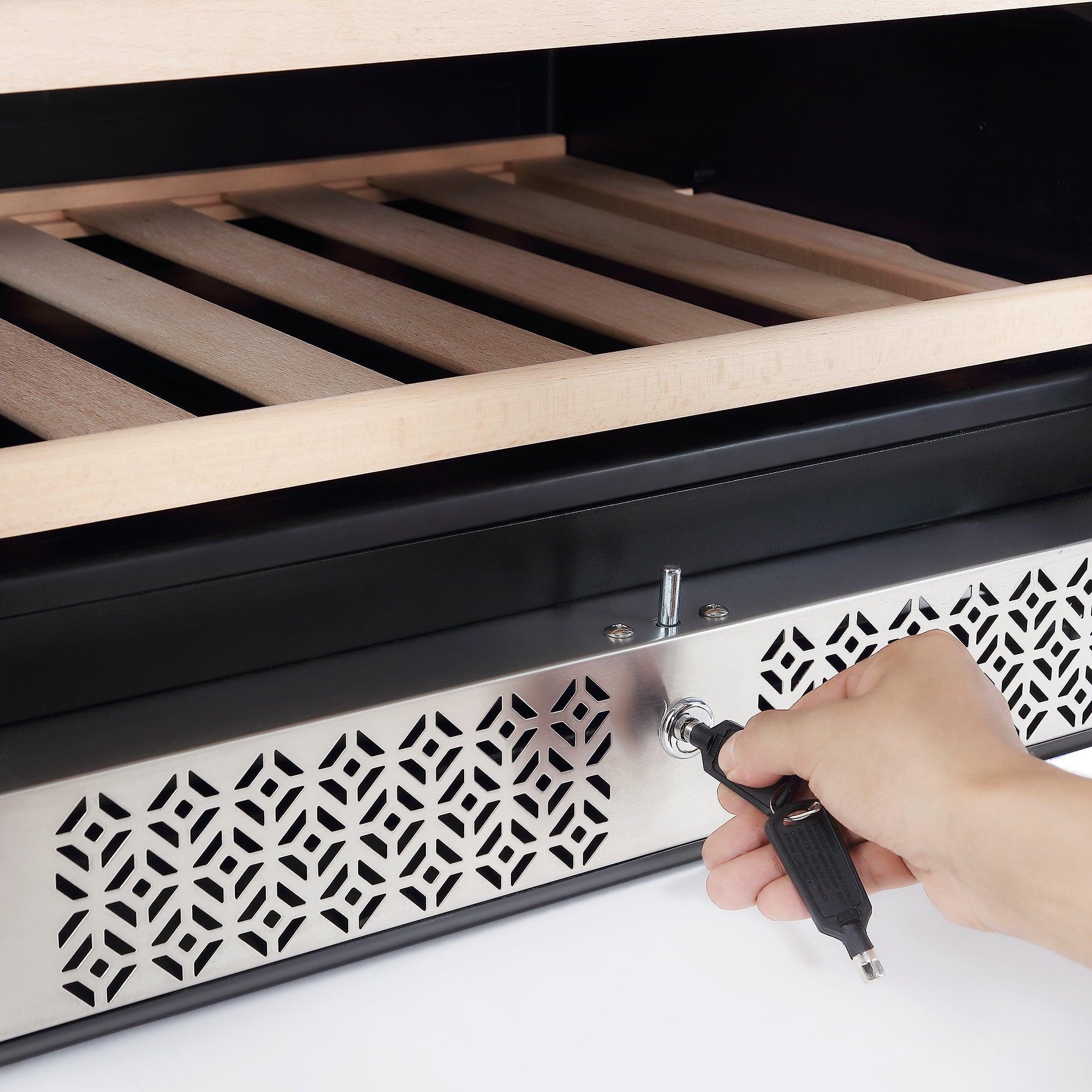 A hand holds a key and is locking or unlocking the front panel of the Empava Wine Cooler 70" Tall Wine Fridge, which has a metallic, perforated ventilation pattern. Above the panel, wooden slats and movable racks inside the wine cooler suggest it could be a compartment with an enormous capacity for storage.