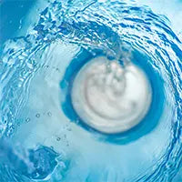 A close-up image of water from the Custom Function swirling around a sink drain, creating a vortex effect. The water appears clear while the drain is slightly blurred due to motion. The overall color scheme is primarily blue due to the water.