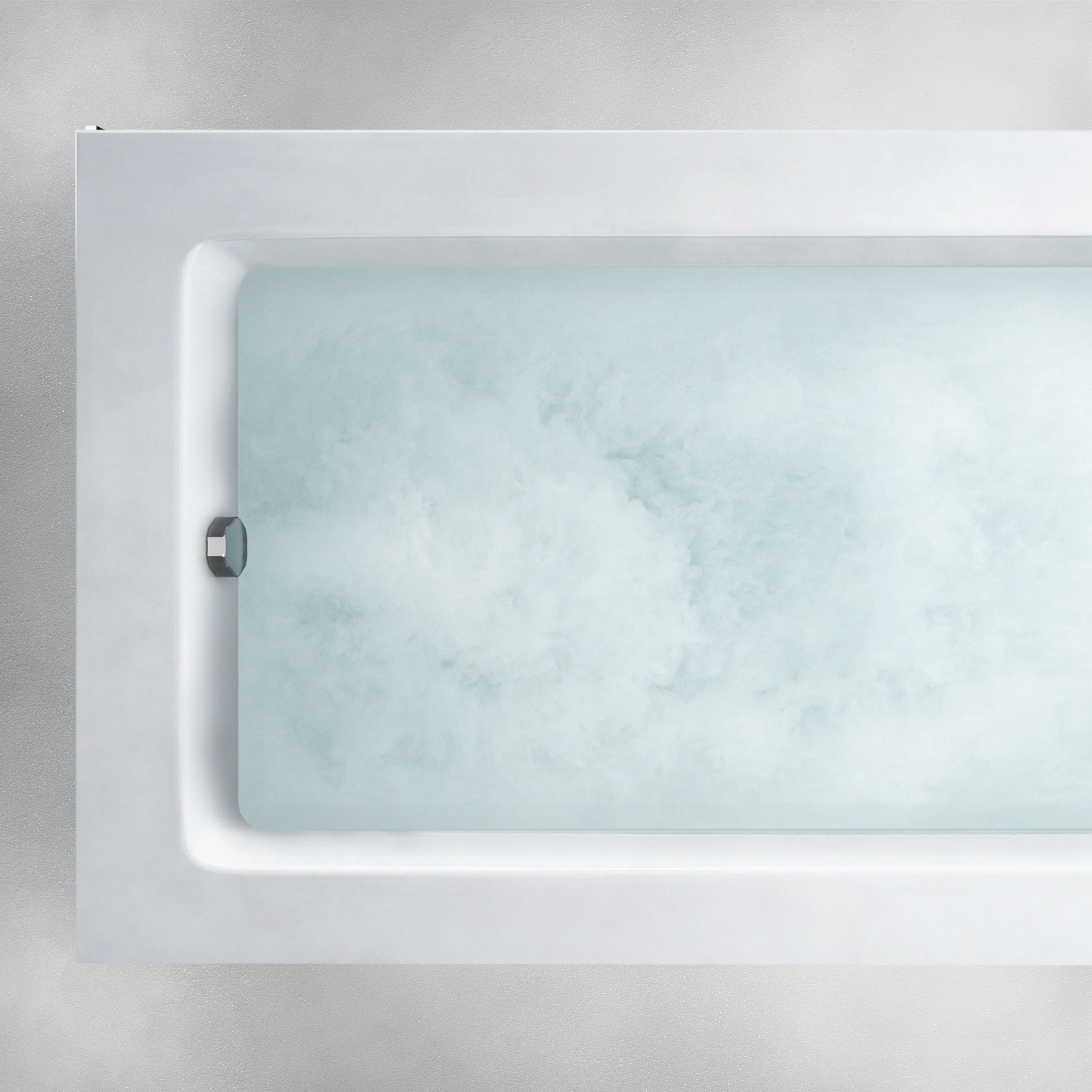 A top-down view of the Custom Function rectangular white bathtub filled with slightly cloudy water. The bathtub showcases a simple, modern design with straight edges against a minimalistic light gray background.